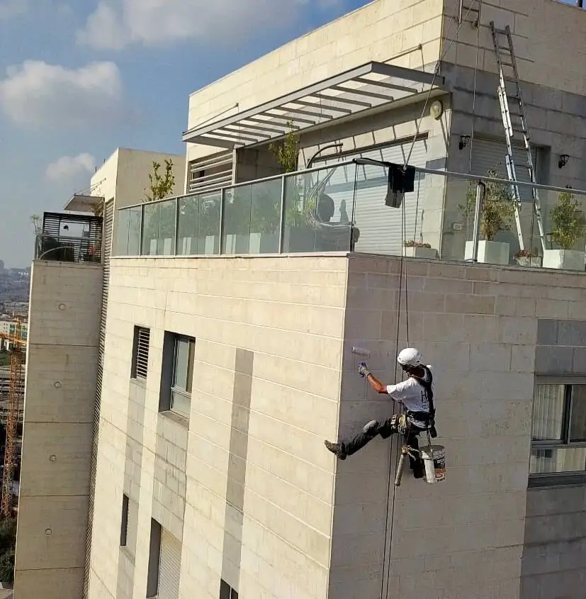 עובד הרמטיקו בסנפלינג מבצע עבודת איטום בגובה על קיר חיצוני